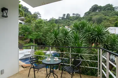 a balcony with a table and chairs and trees at 3-BR Condo Mountain & Pool view, Pool & Gym access - Kamala Hills G201 in Kamala Beach