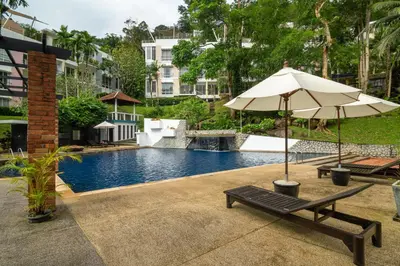 an umbrella and a bench next to a swimming pool at 3-BR Condo Mountain & Pool view, Pool & Gym access - Kamala Hills G201 in Kamala Beach