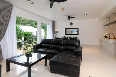 a living room with a black leather couch and a table at 3-BR Condo Mountain & Pool view, Pool & Gym access - Kamala Hills G201 in Kamala Beach
