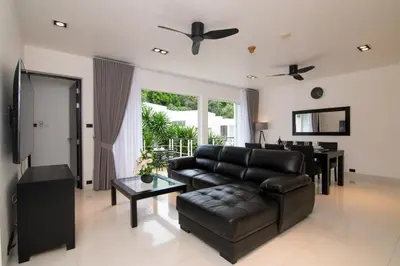 a living room with a black leather couch and a table at 3-BR Condo Mountain & Pool view, Pool & Gym access - Kamala Hills G201 in Kamala Beach
