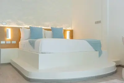 a white bedroom with a white bed with blue pillows at Loft with pool & patio - 8 min to Rawai beach - 