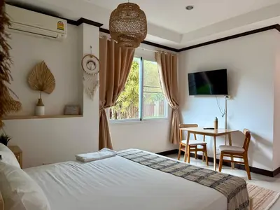 a bedroom with a bed and a table and a window at Jungle style apartments in Kamala in Kamala Beach