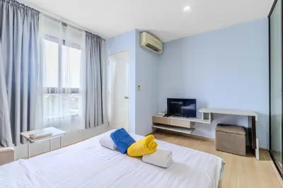 a bedroom with a white bed with blue and yellow pillows at C232 Prime spot Pool Gym Near Beach&Boat Ave in Bang Tao Beach