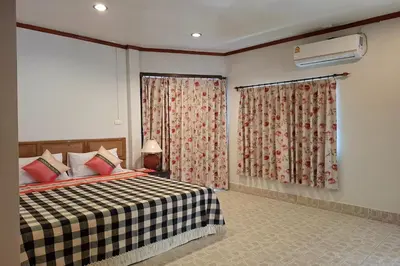 a bedroom with a bed and a window with curtains at Kamala Orchid Guesthouse in Kamala Beach