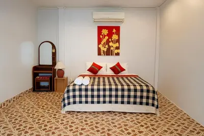a bedroom with a bed with red pillows on it at Kamala Orchid Guesthouse in Kamala Beach