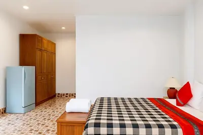 a bedroom with a bed and a refrigerator at Kamala Orchid Guesthouse in Kamala Beach