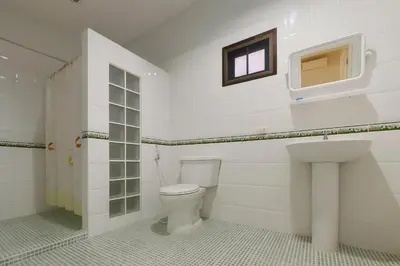 a white bathroom with a toilet and a window at Kamala Orchid Guesthouse in Kamala Beach