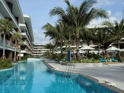 a swimming pool with palm trees and a building at The Sunshine Beach 3-bedrooms Suite with Pool in Layan Beach