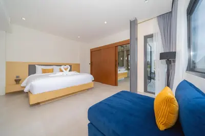 a bedroom with a bed and a blue couch at Riverhouse Phuket - Private Pool Villas by Escape Villas in Laguna Phuket