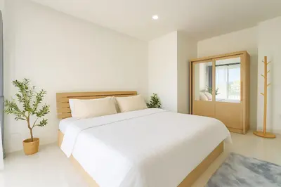 a white bedroom with a large bed and a window at Dalbit Thai Stay 2 Bedroom Patong house - 8mins walk to Jungcyelon Bangla Rd in Patong Beach