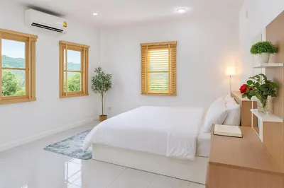 a white bedroom with a bed and two windows at Dalbit Thai Stay 2 Bedroom Patong house - 8mins walk to Jungcyelon Bangla Rd in Patong Beach