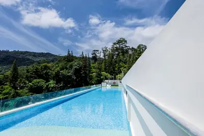 an infinity pool in a villa with trees at Modern 2BR apartment on Kamala Beach in Kamala Beach