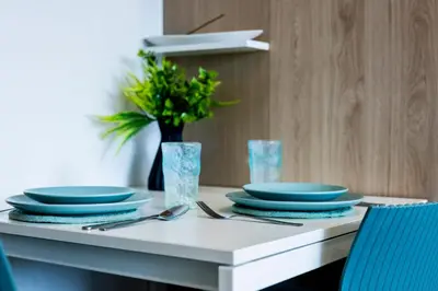 a table with blue plates and a vase with a plant at The Signature Suite in Ban Mai Salae