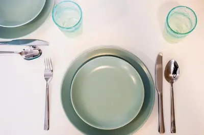 a white table with a green plate and silverware at The Signature Suite in Ban Mai Salae