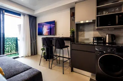 a kitchen with a counter and chairs in a room at The Signature Suite in Ban Mai Salae