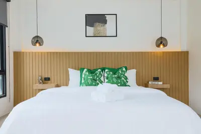 a bedroom with a large white bed with green pillows at Wink Hill 4 Penthouse Patong Beach 4Beds in Patong Beach