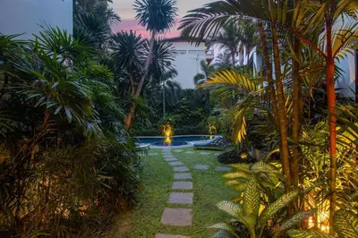 a garden with a path leading to a pool with palm trees at C233 Condo 650m Surin 1BR with Pool &Gym Prime Location in Surin Beach