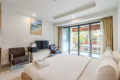 a hotel room with a bed and a tv and a balcony at C233 Condo 650m Surin 1BR with Pool &Gym Prime Location in Surin Beach