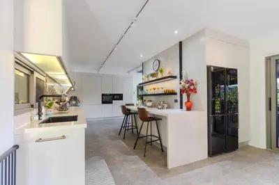 a kitchen with white cabinets and a bar with stools at V238 Villa 6BR Lakefront Jacuzzi Sauna & Gym, Near Beach in Rawai Beach