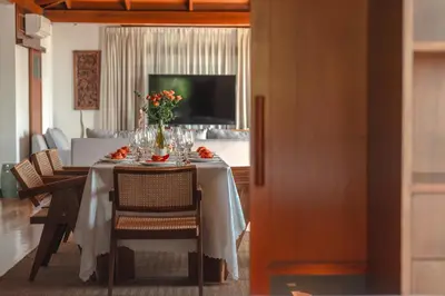 a dining room table with a vase of flowers on it at Surin Ayara Villas by Stayisle in Surin Beach