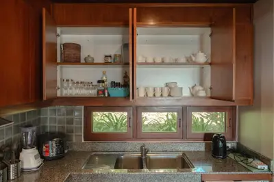 a kitchen with wooden cabinets and a sink at Surin Ayara Villas by Stayisle in Surin Beach
