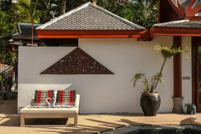 a bench with two pillows on it next to a house at Surin Ayara Villas by Stayisle in Surin Beach