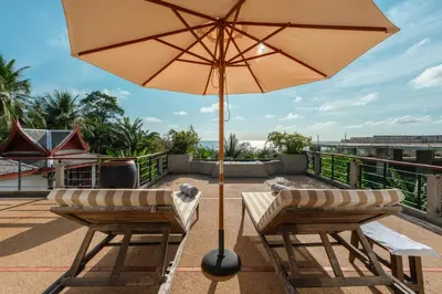 a patio with two chairs and an umbrella at Surin Ayara Villas by Stayisle in Surin Beach
