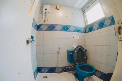 a bathroom with a blue toilet and a window at Mitr Inn Phuket OldTown - มิตรอินน์ โอลด์ทาวน์ in Phuket Town
