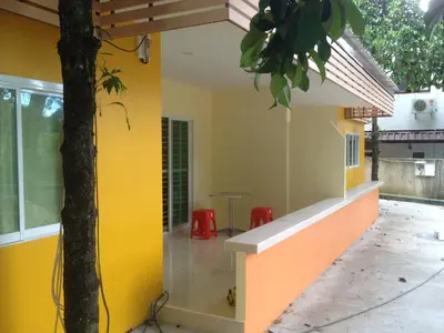 a building with yellow and orange walls and a tree at Kathu Waterfall Bungalow in Kathu