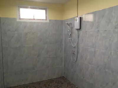 a shower in a bathroom with a tile wall at Kathu Waterfall Bungalow in Kathu