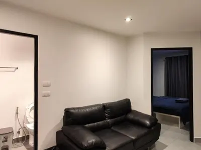 a living room with a leather couch and a bed at Chalong Bay - One bedroom on 7 Floor at Tower 1 in Ban Klang