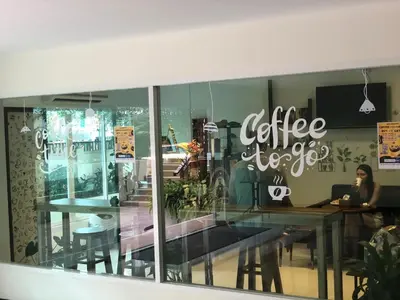 a coffee shop window with a woman sitting at a table at Phuket Villa Patong Pool-Garden View in Patong Beach