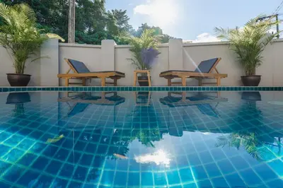 a swimming pool with two chairs and a table next to it at Naiharn Beach Holiday Pool Villa, Rawai in Rawai Beach