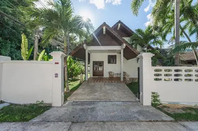 a house with a white fence and palm trees at Naiharn Beach Holiday Pool Villa, Rawai in Rawai Beach