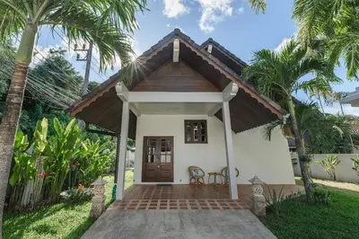 a small white house with a porch and palm trees at Naiharn Beach Holiday Pool Villa, Rawai in Rawai Beach