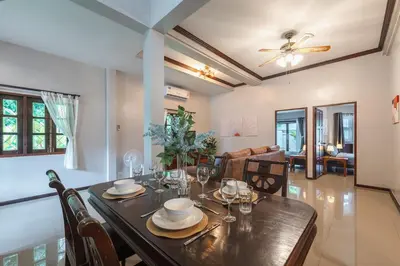 a dining room with a wooden table and chairs at Naiharn Beach Holiday Pool Villa, Rawai in Rawai Beach