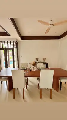 a dining room with a wooden table and white chairs at Phuket Cozy Villa Pasak4 Green Garden BangTao in Laguna Phuket