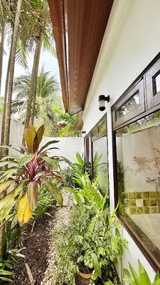 a patio with plants and a building with a window at Phuket Cozy Villa Pasak4 Green Garden BangTao in Laguna Phuket