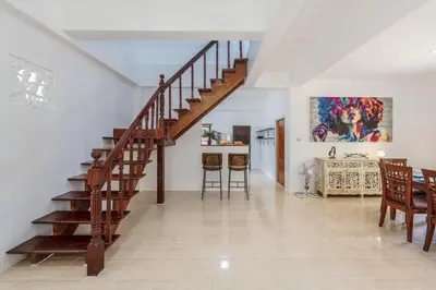 a staircase in a living room with a table and a kitchen at Naiharn Beach Holiday Villa, Rawai Phuket in Rawai Beach