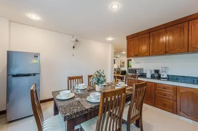 a kitchen with a table with chairs and a refrigerator at Family Sea View Holiday Pool Villa, Saiyuan Phuket in Ban Saiyuan (1)