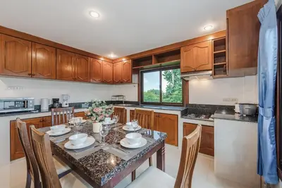 a kitchen with a table and chairs in a kitchen at Family Sea View Holiday Pool Villa, Saiyuan Phuket in Ban Saiyuan (1)