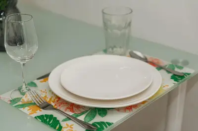 a table with a plate and a fork and knife and a glass at Chic Condo by Bcare - Purple Rose in Karon Beach
