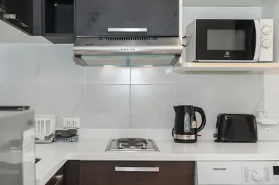 a kitchen with a stove and a microwave at Chic Condo by Bcare - Purple Rose in Karon Beach