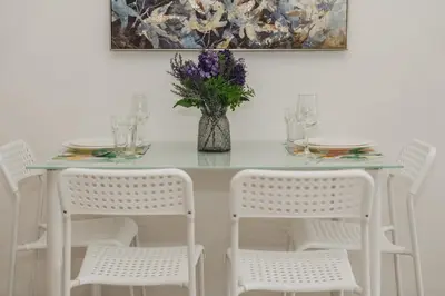 a table with white chairs and a vase with purple flowers at Chic Condo by Bcare - Purple Rose in Karon Beach
