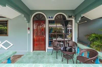 a patio with a table and chairs and a red door at Areca Holiday Home 3, Karon Beach in Karon Beach