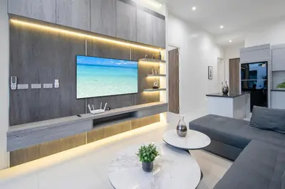 a living room with a couch and a tv on a wall at Luxury Modern Villa Phuket - Thala in Phuket