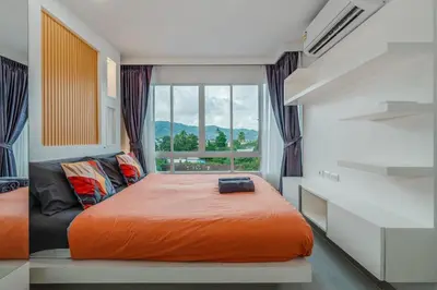 a bedroom with an orange bed and a window at A Stylish Condo in Local Area Kathu, Phuket in Kathu