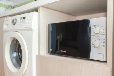 a microwave next to a washing machine on a shelf at A Nice Condo in Local Livelyhood of Kathu in Kathu