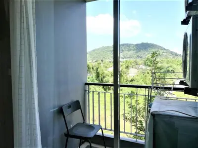 a chair in front of a window with a mountain view at A Fully Furnished Condo in the Phuket Center in Ban Ket Ho