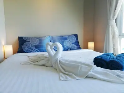 two white swans are sitting on a bed at A Fully Furnished Condo in the Phuket Center in Ban Ket Ho